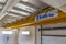 Yellow colored heavy load handling crane mounted on the ceiling ready to use in the closed warehouse area