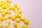 Yellow colorful round dragees of vitamin c, ascorbic acid on pink background, copy space