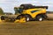 Yellow combine harvester on a wheat field with blue sky