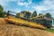 A yellow combine harvests wheat on a field