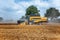 A yellow combine harvests wheat on a field