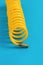 A yellow compressor hose twisted into a spiral on a blue background