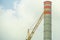 Yellow construction crane with a water tank white with orange with the sky