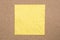 Yellow creased paper note on cork background