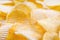 Yellow crispy ridged potato chips close up. Food background