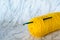 Yellow crochet yarn with crochet hook on neutral background