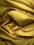 Yellow crumpled fabric bed sheets texture view from above background