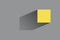 Yellow cube with a sharp shadow on a gray background. Colored in 2021 color trends Ultimate Gray and Illuminating.