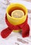 Yellow cup wrapped scarf and hot tea with lemon, warming beverage for autumn or winter evening