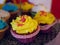 Yellow cupcake frosted with many colorful cupcakes