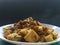 Yellow curry tofu fried on white dish with hot smoke on black background