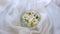 Yellow dandelions, white blooming flowers, green leaves in a bowl of water on a white thin material