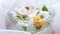 Yellow dandelions, white blooming flowers, green leaves floating in a bowl of water on a white material