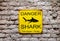 Yellow Danger Shark sign on brick wall