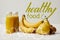 yellow detox smoothies in bottles with bananas, pears and kiwis on white background, healthy