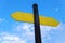 Yellow direction sign on the pole against the blue sky. Yellow arrow signal against sky