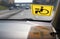 Yellow disabled driver sign on windshield of car. View from inside vehicle. Reflection of sticker on dashboard