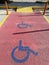 Yellow disabled-person sign marking a space at a parking lot, on a red background