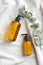 Yellow dispenser bottles and eucalyptus leaf on white towel in bathroom.