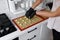 The yellow dough from the pastry syringe is squeezed out on a baking sheet.