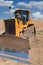 Yellow dozer on a dirt terrain with blue sky