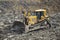 Yellow dozer pushes large piles of dirt