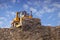 Yellow dozer pushes a pile of sand