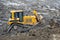 Yellow dozer pushing huge pile of dirt