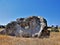 On the yellow dried grass, against the blue sky, stands a large picturesque stone.