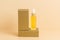 Yellow dropper bottle of serum or oil standing on golden podium with neutral beige background. Organic skin care