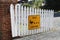A Yellow duck crossing sign is on a white picket fence