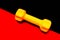 Yellow dumbbell for fitness on red and black background