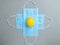Yellow easter egg lies on blue medical masks on a gray background