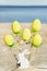 Yellow easter eggs, wooden rabbit are on the beach with sea.