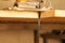 A yellow electric jigsaw ready for use stands in a sawn wood building material on a workbench in a workshop for carpentry work.