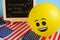 Yellow emoji balloons on the background of the board with the event inscription and American flags.