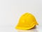Yellow engineer safety hat put on white marble counter top with