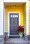 Yellow entry area with dark door and red flowers