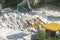 Yellow excavator breaks a brick building in the yard