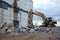 Yellow excavator with bucket at demolition of tall building. Hydraulic machine for demolish