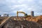 Yellow Excavator at building under construction. Backhoe digs the ground for the foundation and for laying sewer pipes.