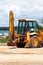 Yellow excavator, bulldozer machine and worker tractor. Road works. Road machinery at construction site.