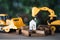 Yellow excavator and bulldozer models with home model on wood block