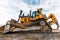 Yellow excavator in career moves overburden. Bulldozer combs the ground, with the bright sun and nice blue sky in the