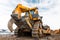 Yellow excavator in career moves overburden. Bulldozer combs the ground, with the bright sun and nice blue sky in the