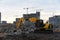 Yellow excavator at a construction site during crushing stones after the demolition of an old building. Salvaging and recycling