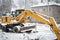 Yellow excavator covered by snow at winter construction site