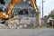 Yellow excavator destroyed a multi-storey building with a chisel tool. The equipment destroys the building, fittings, concrete