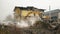 Yellow excavator destroys building. Heavy duty machine is demolishing a brick building. Demolition of the building . Demolition co