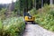 Yellow excavator driving on a mountain trail in coniferous forest in Tatra Mountains, Poland